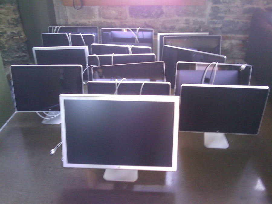 Apple Cinema Displays lined up on a table after the office move